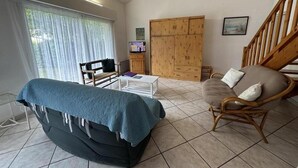 Una sala de estar con sofá, sillón, televisor y un armario de madera.