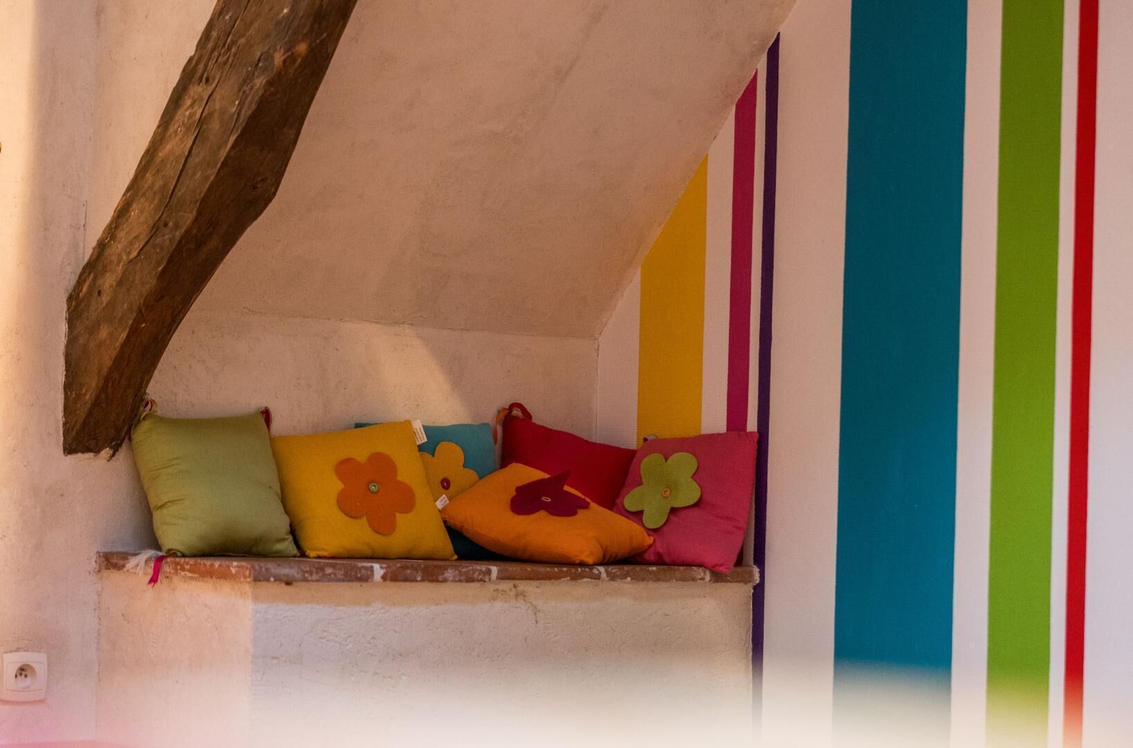 A cozy alcove with colorful cushions and a striped wall.