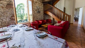 Un espace repas agrémenté d’un mur en pierre, d’un escalier en bois et de meubles rouges.