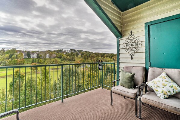Een balkon met uitzicht op een groen landschap en huizen.