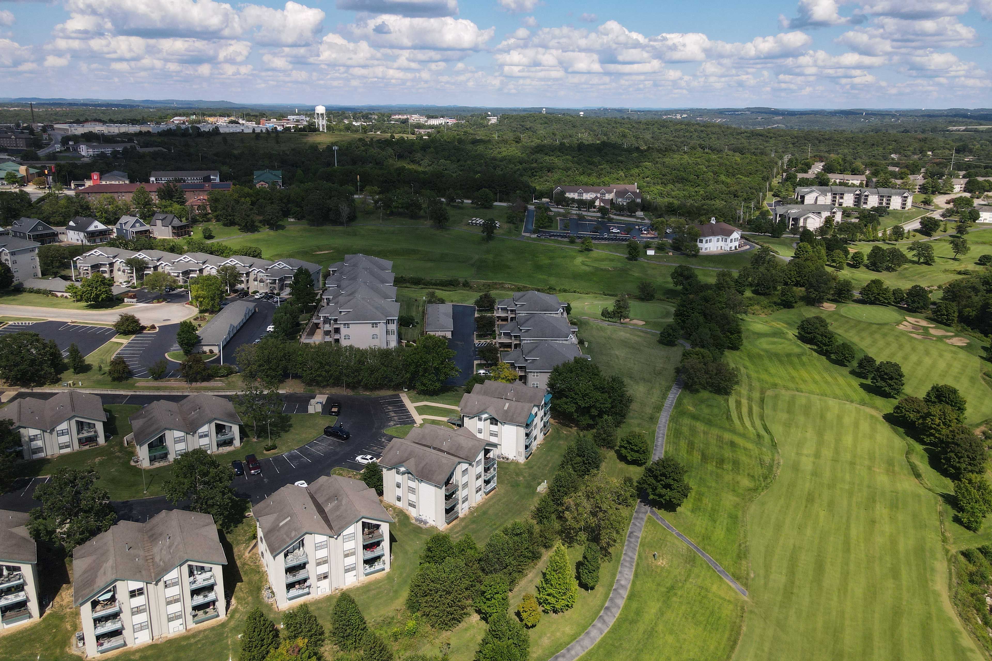 An aerial view of a residential area with multiple apartment buildings, green lawns, and a golf course.