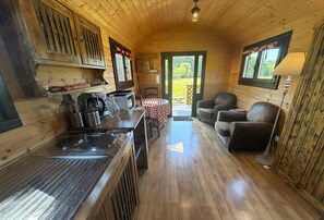 A wooden cabin interior with a kitchen, dining area, and seating.