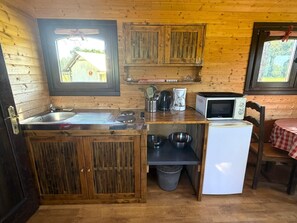 A compact kitchen with wooden cabinets, a sink, a microwave, and a small refrigerator.