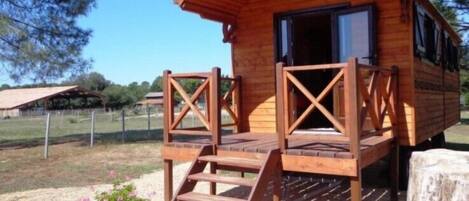 A wooden cabin with a porch and a staircase leading to the entrance.
