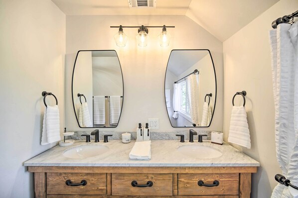 Une salle de bain avec deux lavabos, un grand miroir et un meuble-lavabo en bois doté de tiroirs.