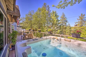 A hot tub on a wooden deck with a view of trees and a fence.