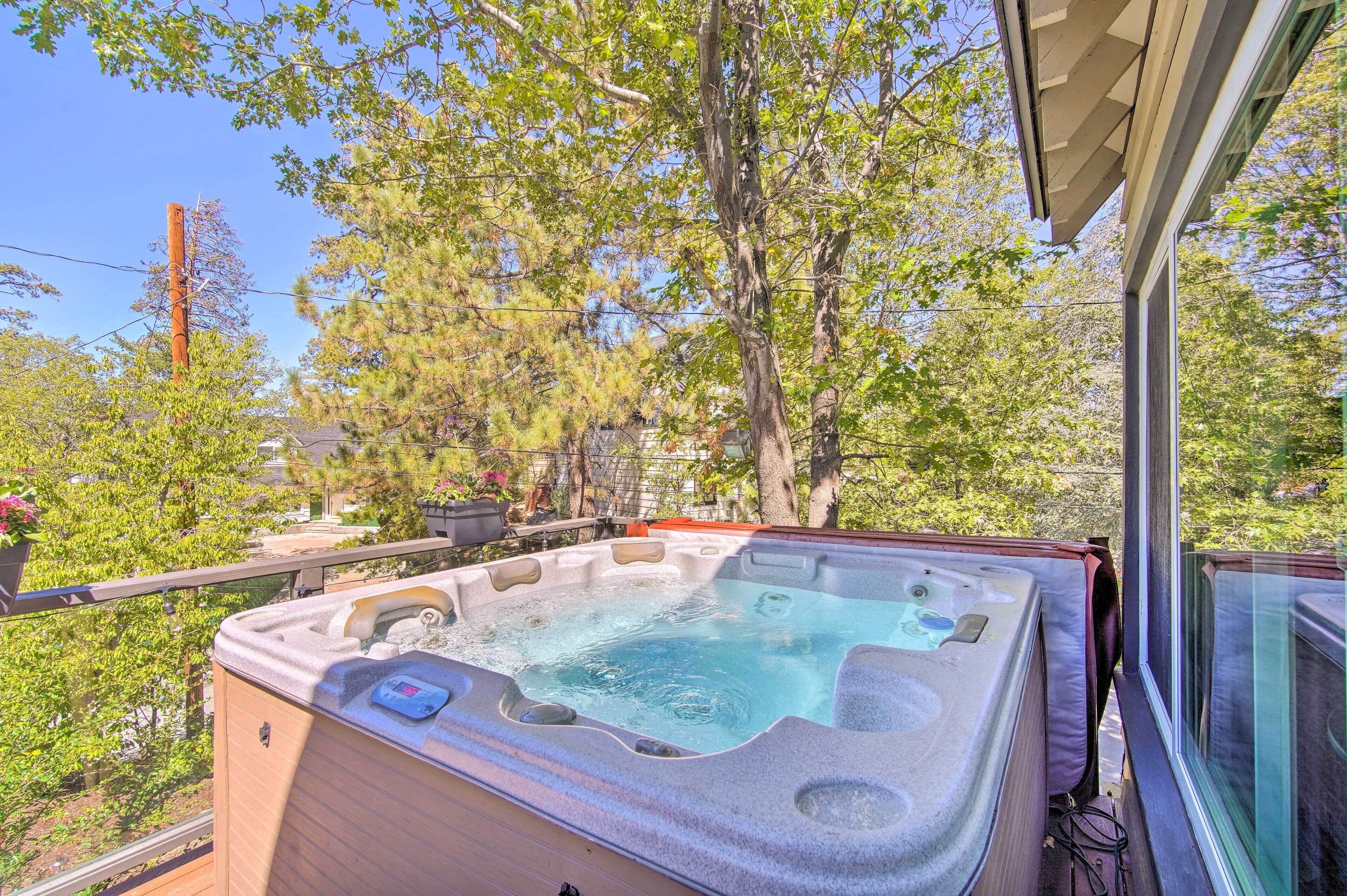 A hot tub on a balcony with a view of trees and a house in the background.