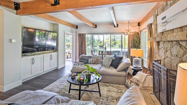 A cozy living room with a stone fireplace, a large TV, and a comfortable seating area. - Chic Lake House w/ Furnished Deck & Hot Tub! (Cedar Glen)