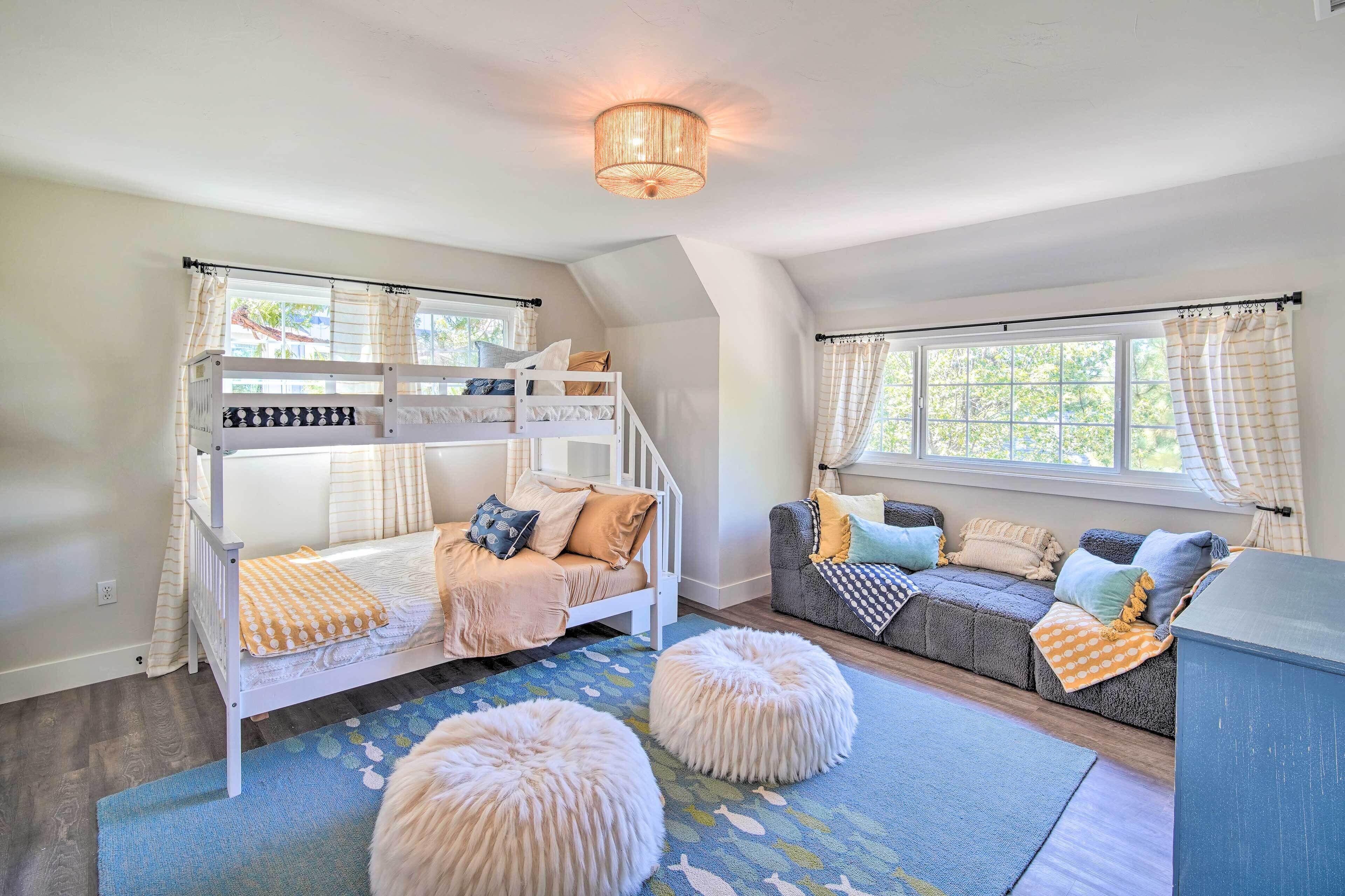 Ein gemütliches Zimmer mit Stockbetten, einer Couch, Poufs und einer Kristallleuchtre.
