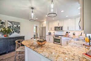 A modern kitchen with white cabinets, granite countertops, stainless steel appliances, and pendant lighting. - Chic Lake House w/ Furnished Deck & Hot Tub! (Cedar Glen)