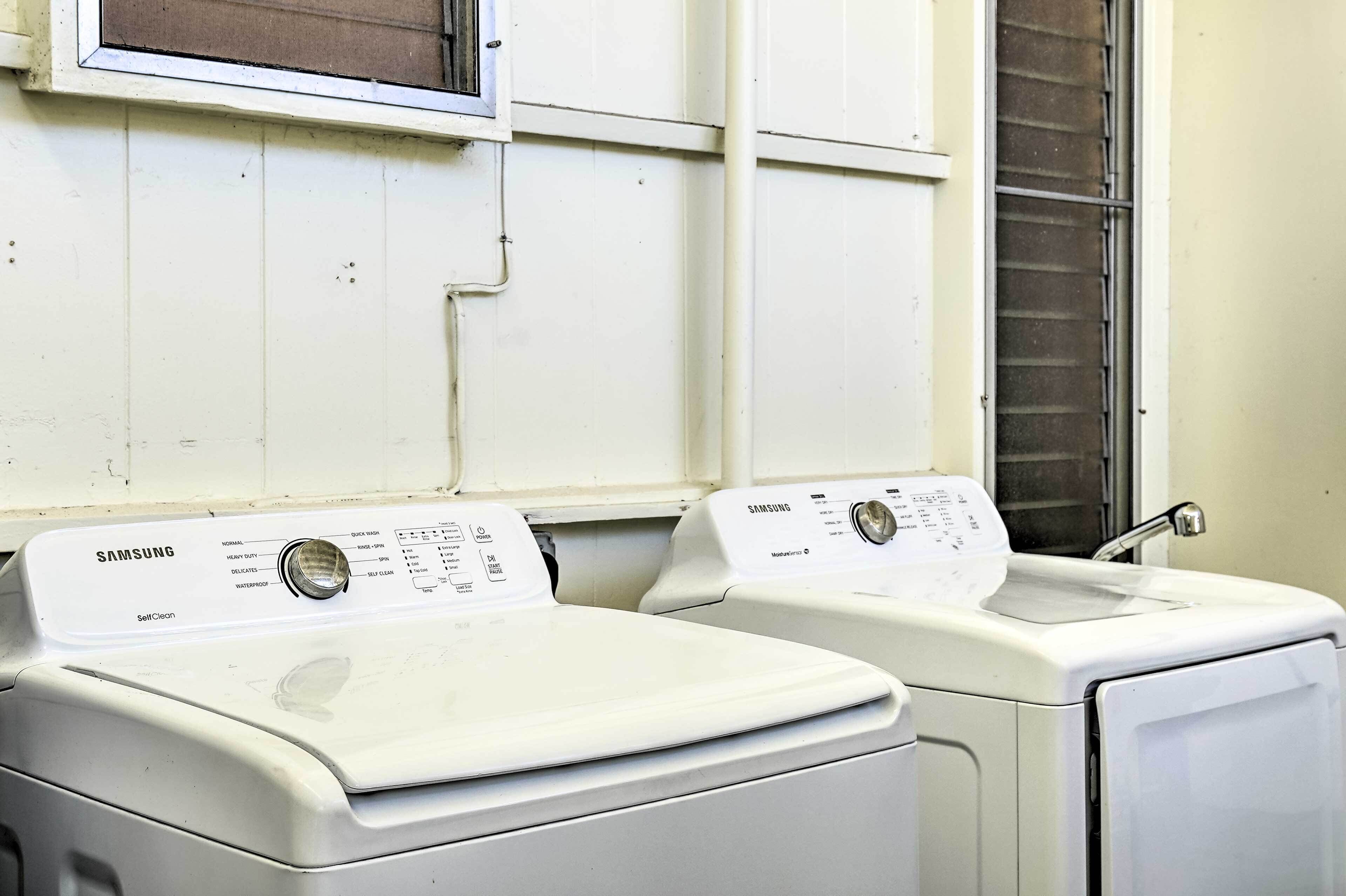 A laundry room with two white Samsung self-cleaning washers and dryers.