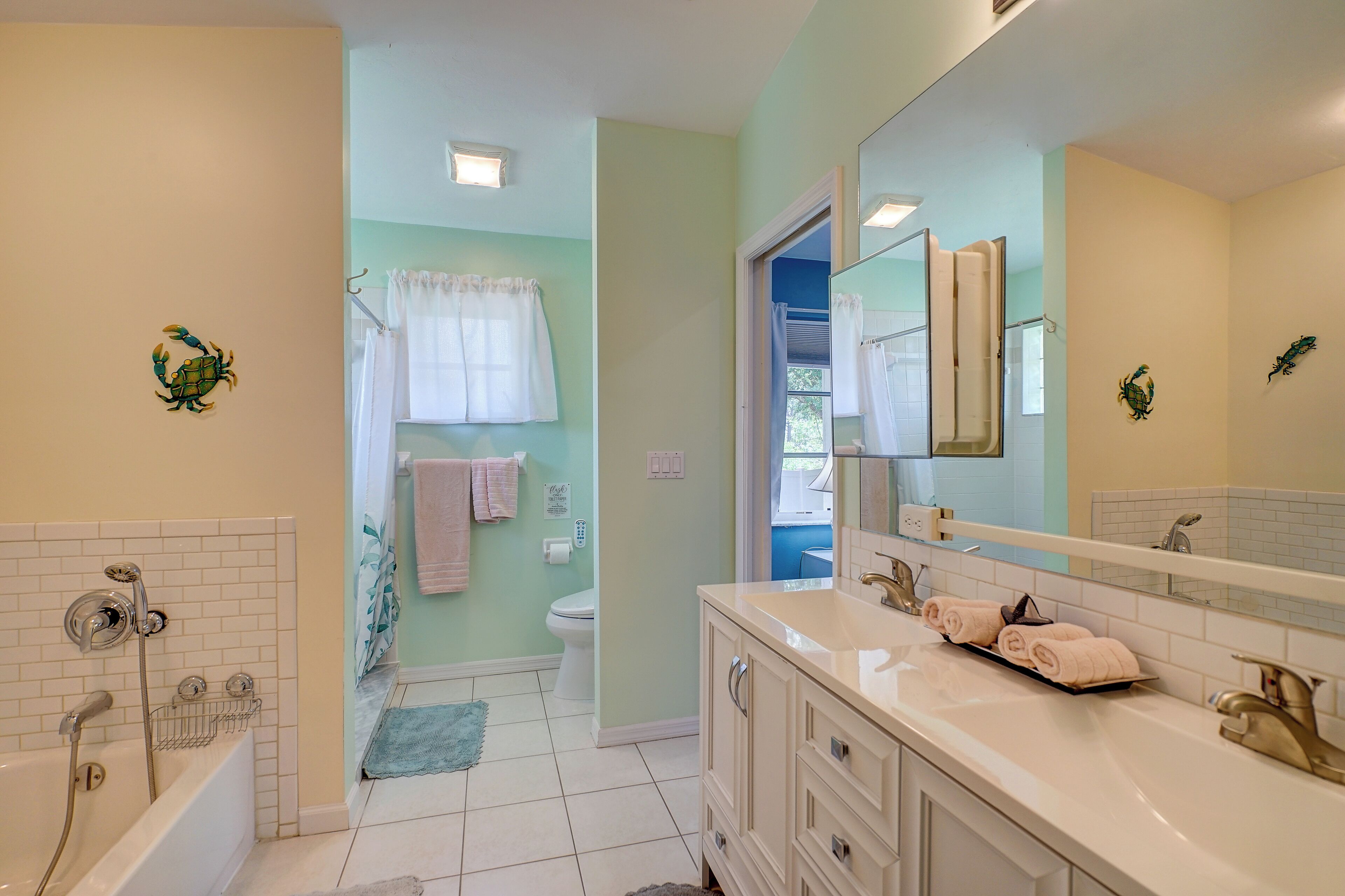 A bathroom with a bathtub, a sink, and a toilet. There are towels on the sink and a shower curtain.