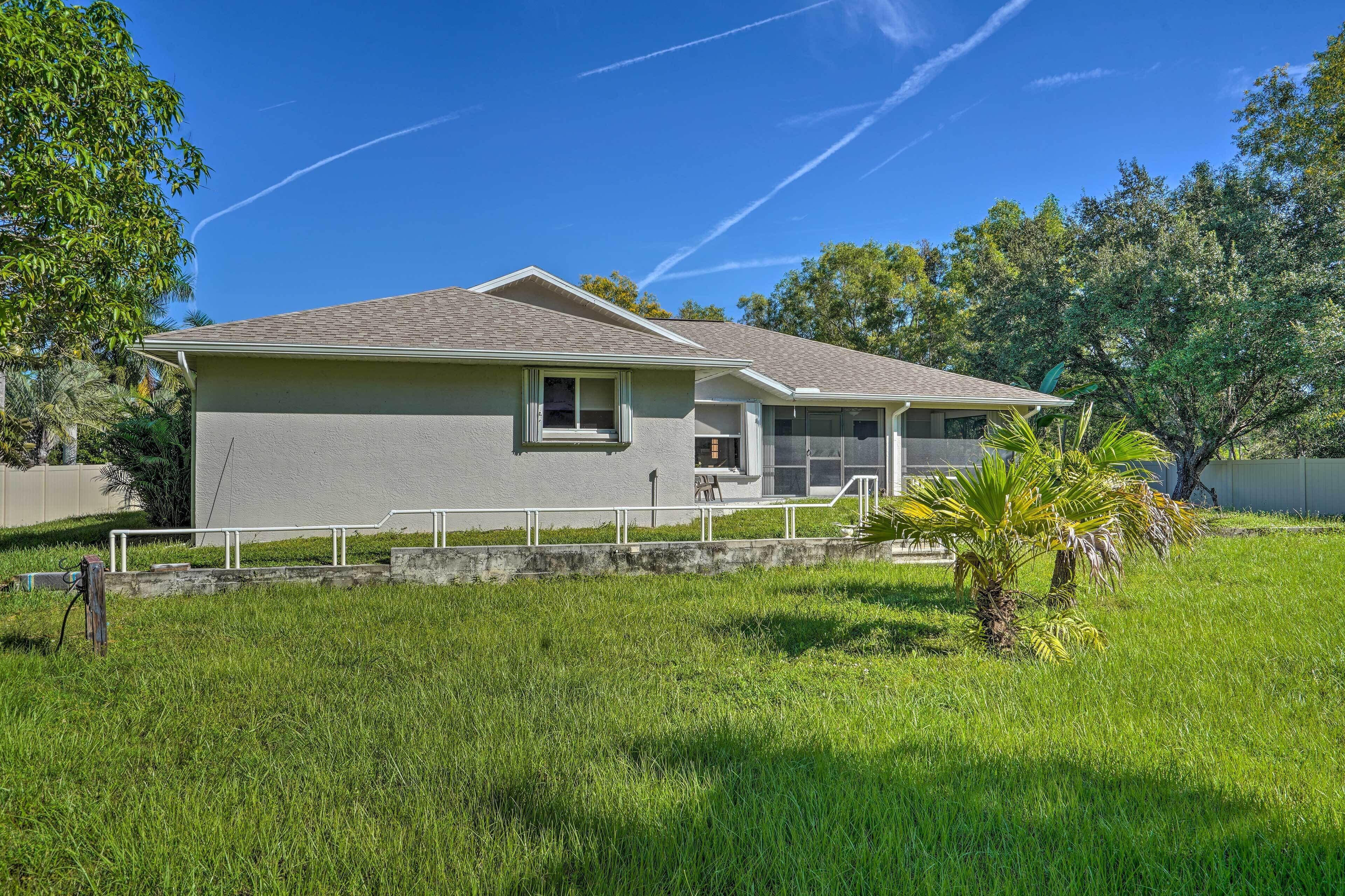 A single-story house with a grey exterior, a front porch, and a small front yard with a palm tree.