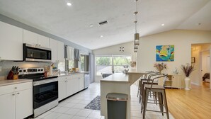 A modern kitchen with white cabinets, stainless steel appliances, and a large island with bar stools. - Game Room & Deck: Spacious Home in St James City (Saint James City)