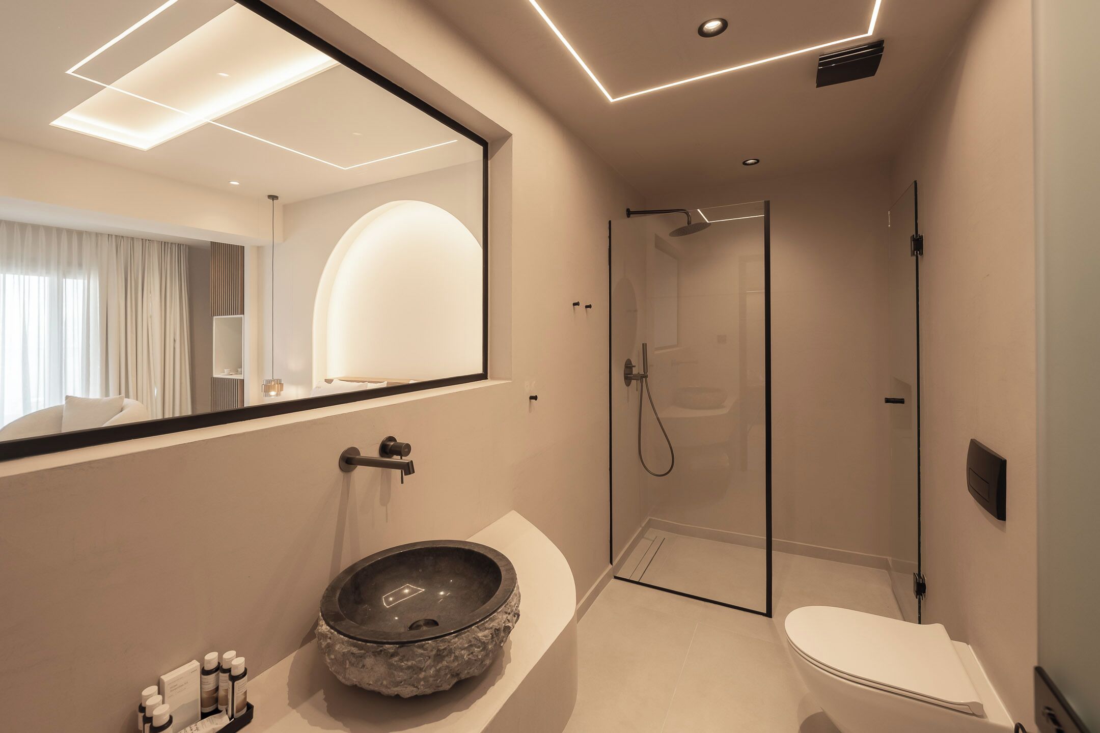 Un baño moderno con ducha envuelta en vidrio, un lavamanos tipo cuenco y un espejo grande.