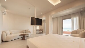 A modern hotel room with a large bed, a sofa, a TV, and a balcony with a view. - Ikyma Boutique (Kassandra)