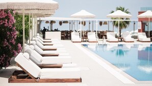 A poolside area with sun loungers and umbrellas, a clear sky, and a pool. - Ikyma Boutique (Kassandra)