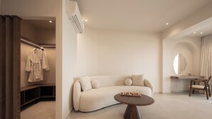 A modern, minimalist living room with a beige sofa, a round coffee table, and a built-in desk with a mirror. - Ikyma Boutique (Kassandra)