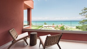 A balcony with two wicker chairs, a wooden stool, and a view of the ocean and resort buildings. - Ikyma Boutique (Kassandra)