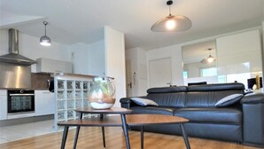 Ein modernes Wohnzimmer mit einem schwarzen Ledersofa, einem Holztisch und einer Glasfischkugel auf einem Beistelltisch.
