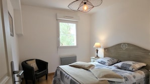 Ein Schlafzimmer mit Bett, Stuhl, Fenster und Lampe.