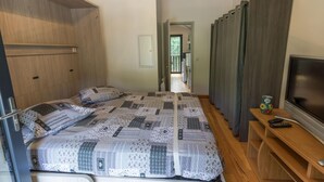 A bedroom with a bed, a TV, and a wooden wardrobe. - Côté Lac - Leon - Gîte (LEON)