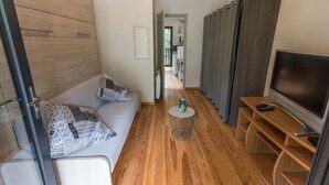 A modern interior with a sofa, a TV, and a small table. - Côté Lac - Leon - Gîte (LEON)