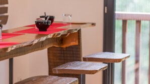 A wooden bar with red placemats and stools. - Côté Lac - Leon - Gîte (LEON)