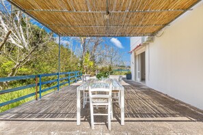An outdoor patio with a table and chairs, a blue railing, and a covered area with a bamboo roof. - 3335 Podere Li Noci by Barbarhouse (Melendugno)