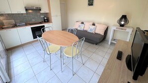 Una cocina compacta con zona de comedor, un sofá y un televisor.