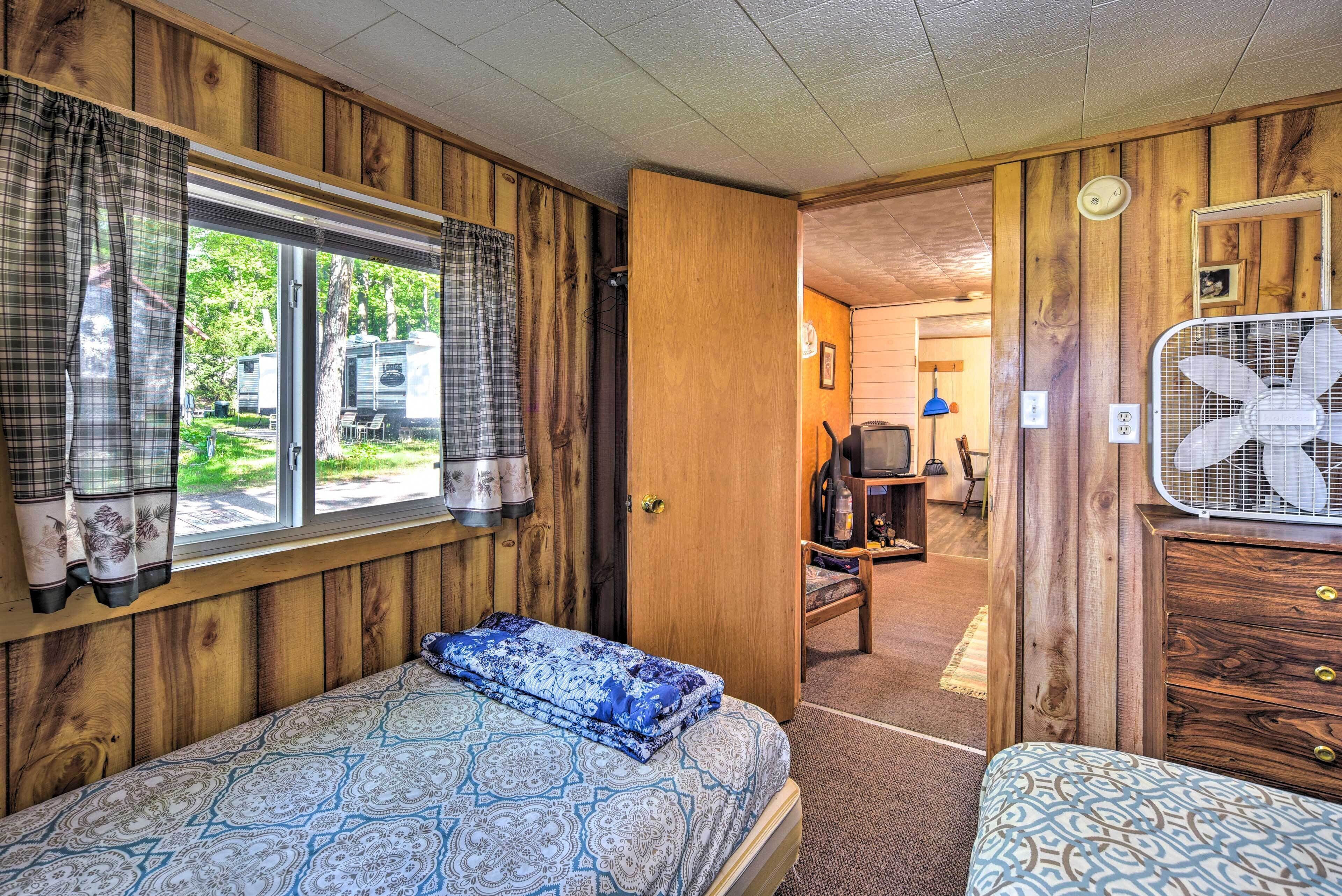 A bedroom with a bed, a dresser, and a window with curtains.