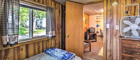 A bedroom with a bed, a dresser, and a window with curtains.