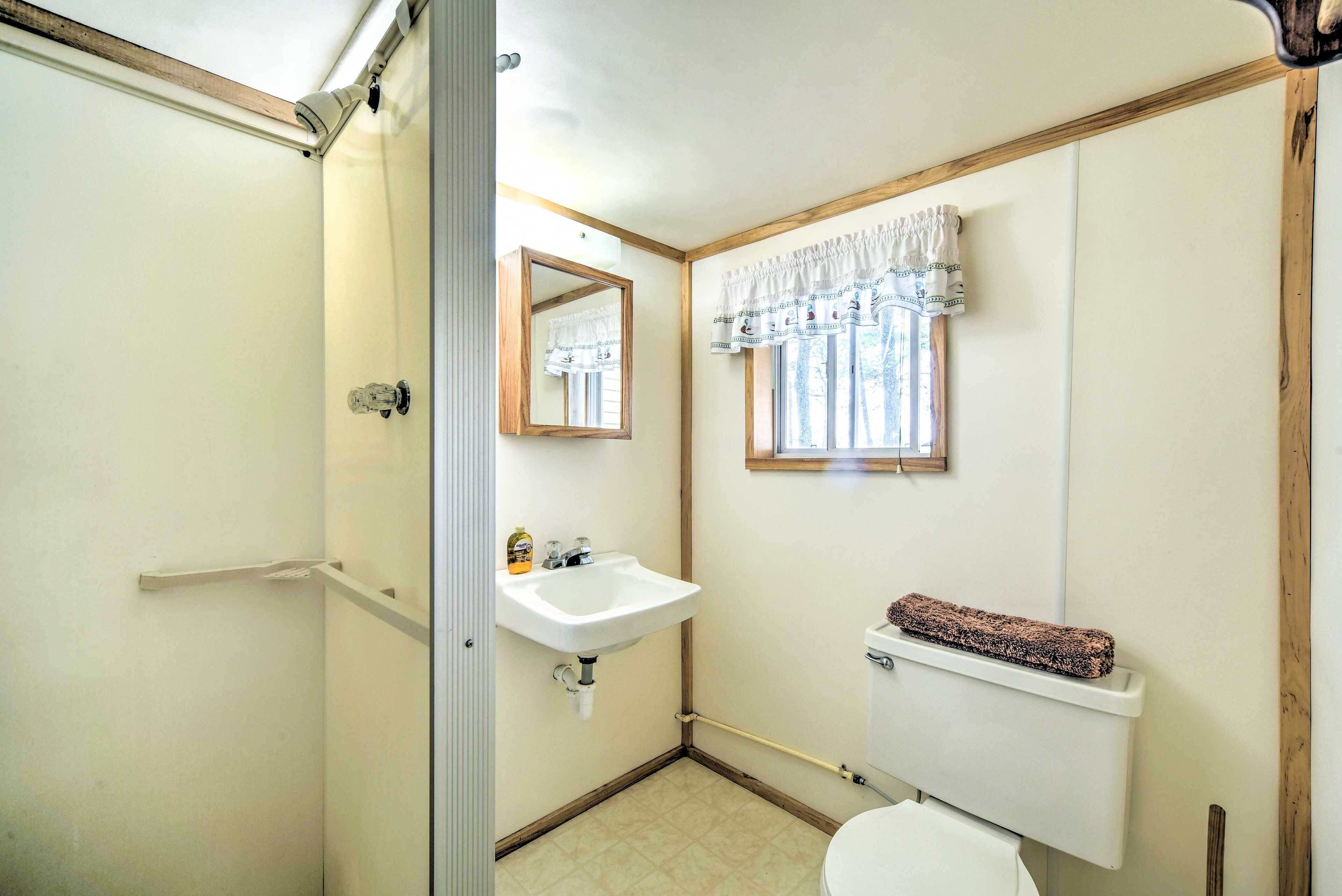 A small bathroom with a toilet, sink, and mirror.