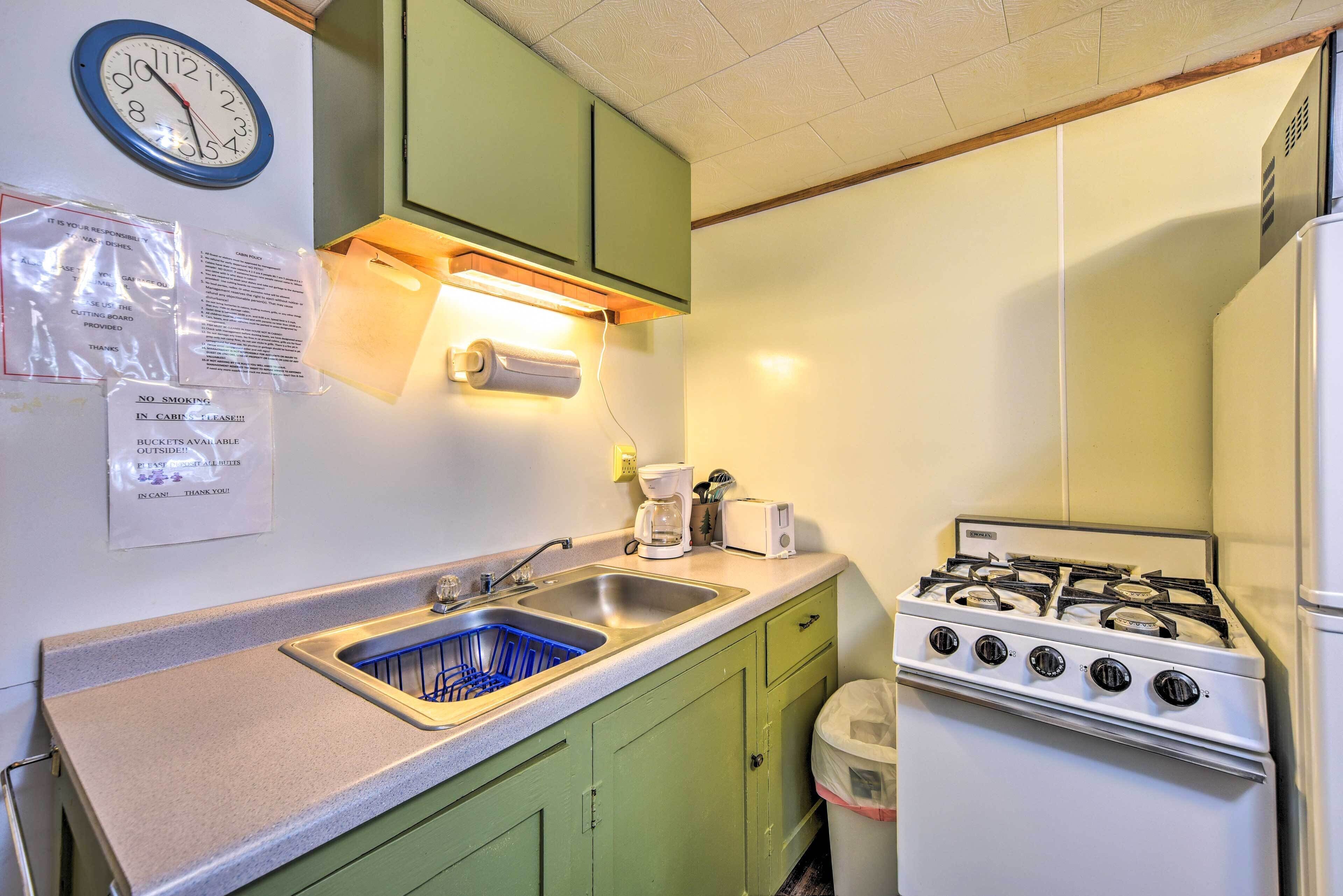 A kitchen with a sink, stove, and green cabinets.