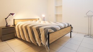 Un dormitorio con cama, mesitas de noche, lámpara y armario.