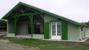 Un edificio de una sola planta con techo verde y ventanas enmarcadas en verde.