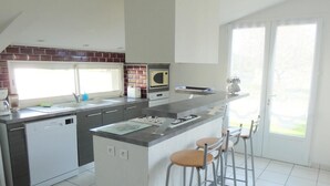 Una cocina moderna con una isla central, taburetes de bar, microondas y lavavajillas.