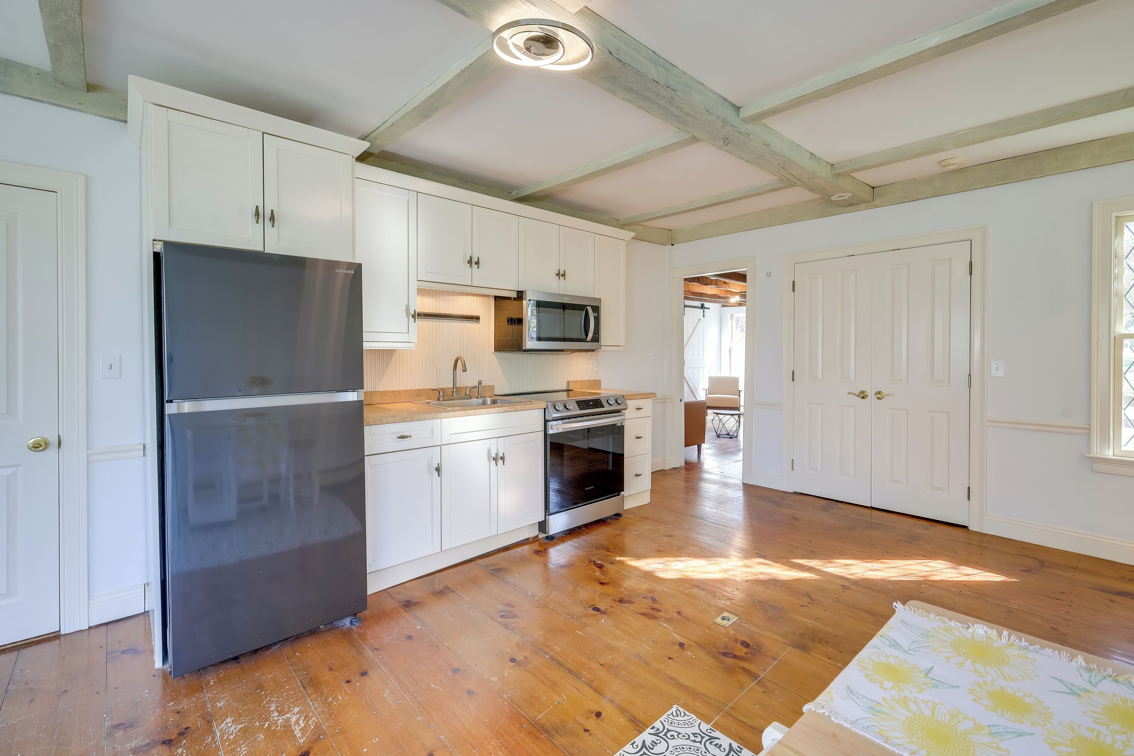 A kitchen with white cabinets, a stainless steel refrigerator, a microwave, and an oven.