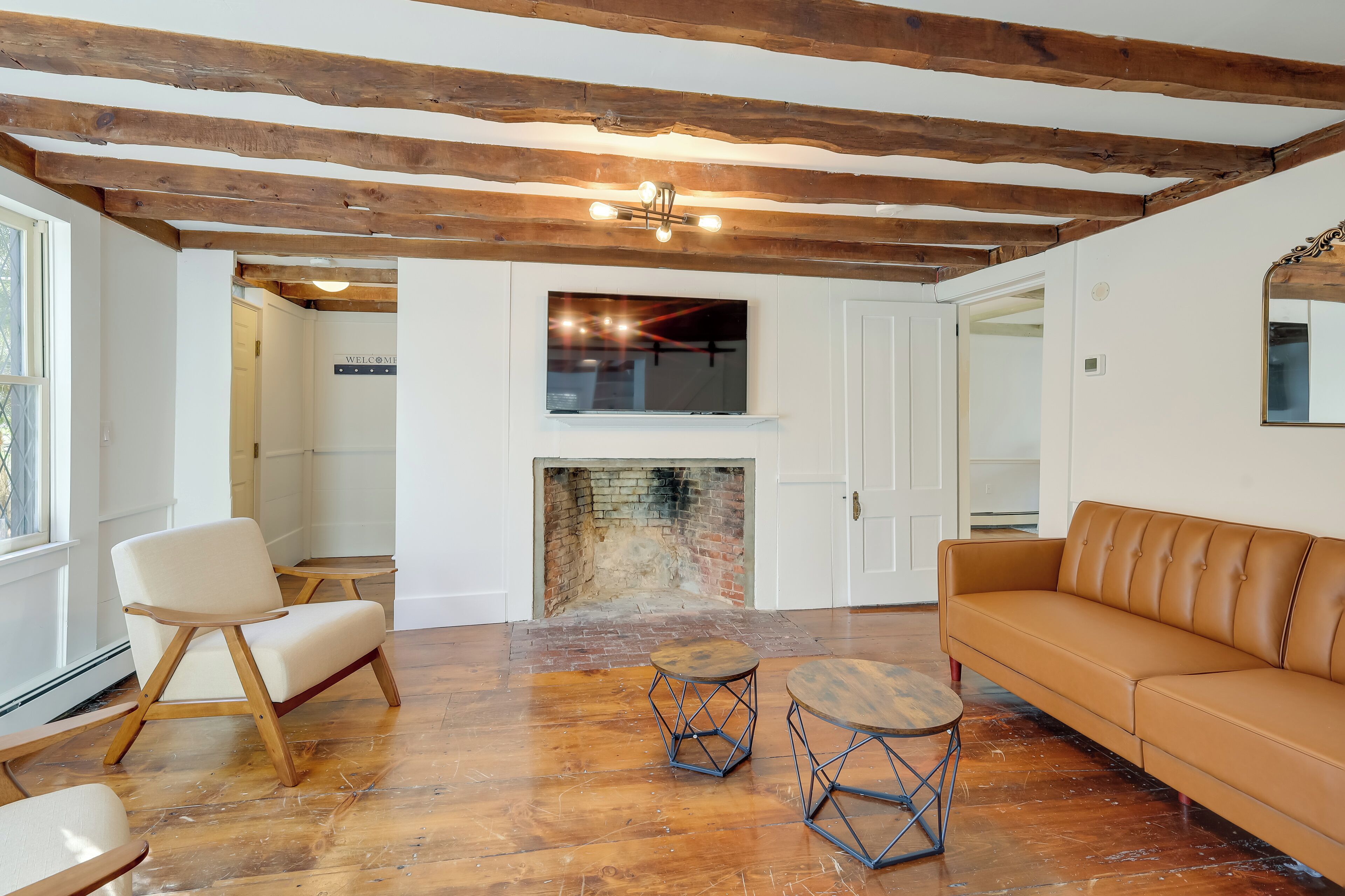 A spacious living room with a fireplace, wooden beams, and a leather sofa.