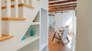 Eine Treppe mit hölzernen Geländern und weißen Wänden, die zu einem Raum mit einem weißen Stuhl und Holzboden führt.