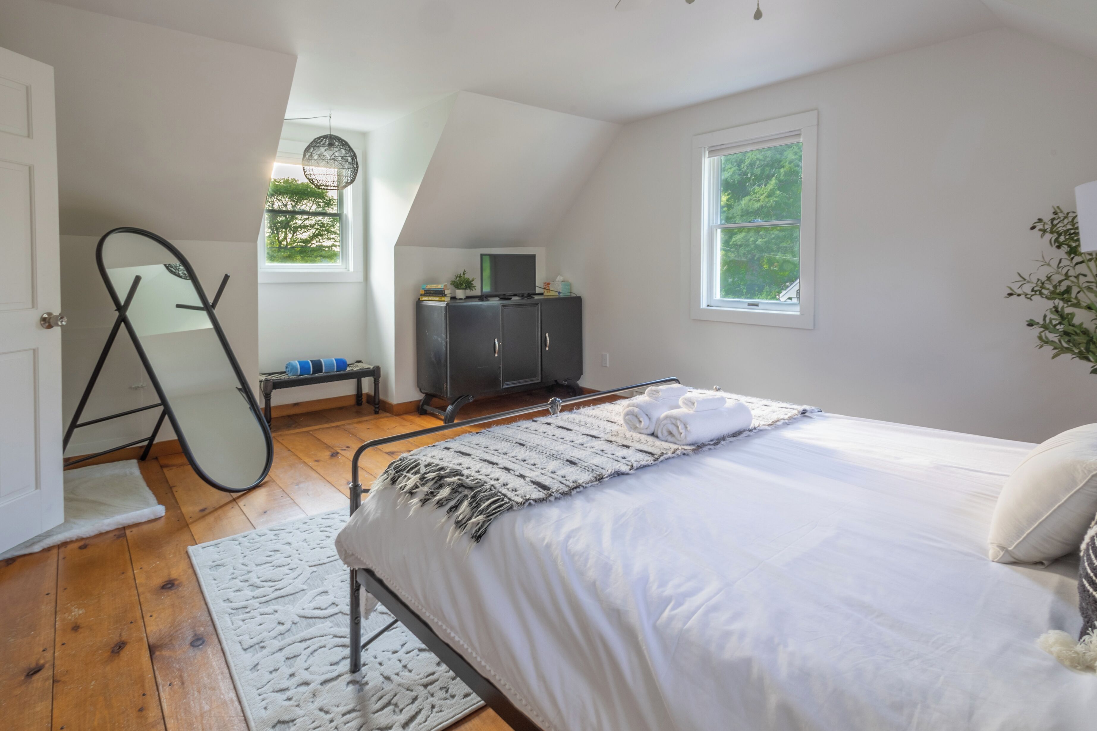 A bedroom with a bed, a dresser, a mirror, and a window.