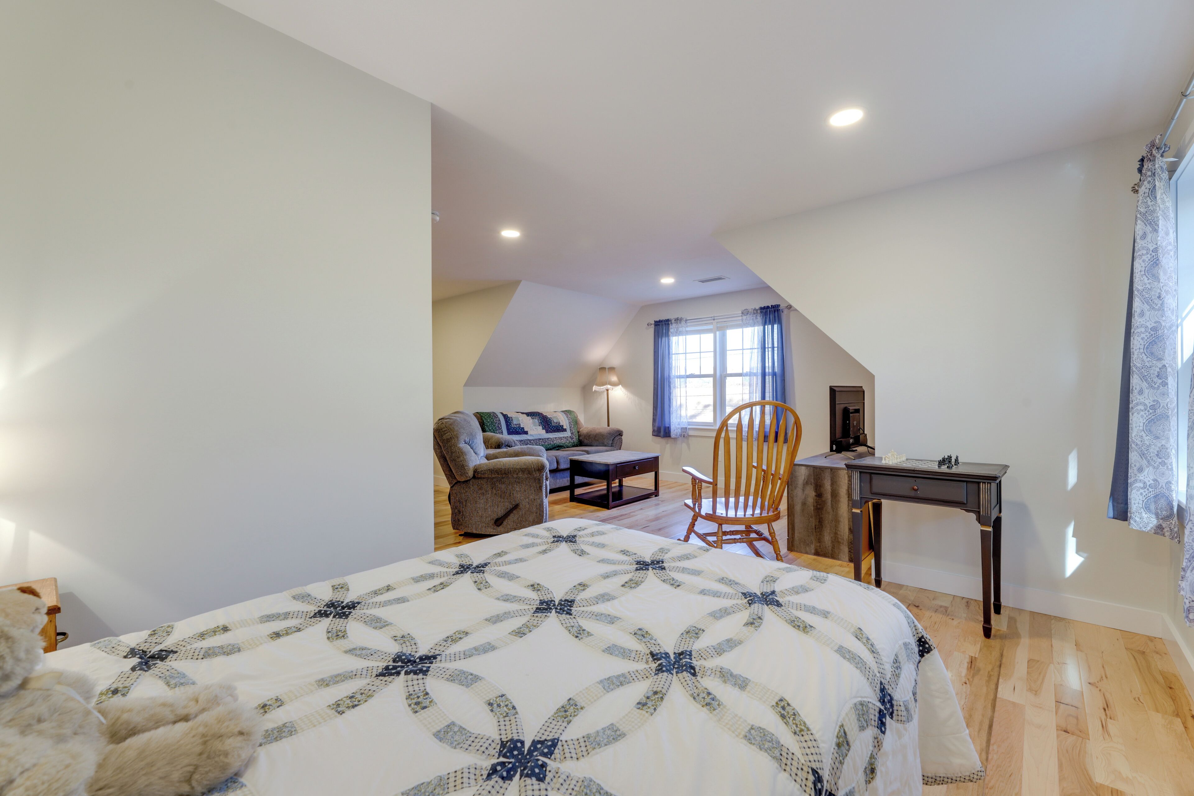 A bedroom with a large bed, a desk, a chair, and a sofa.