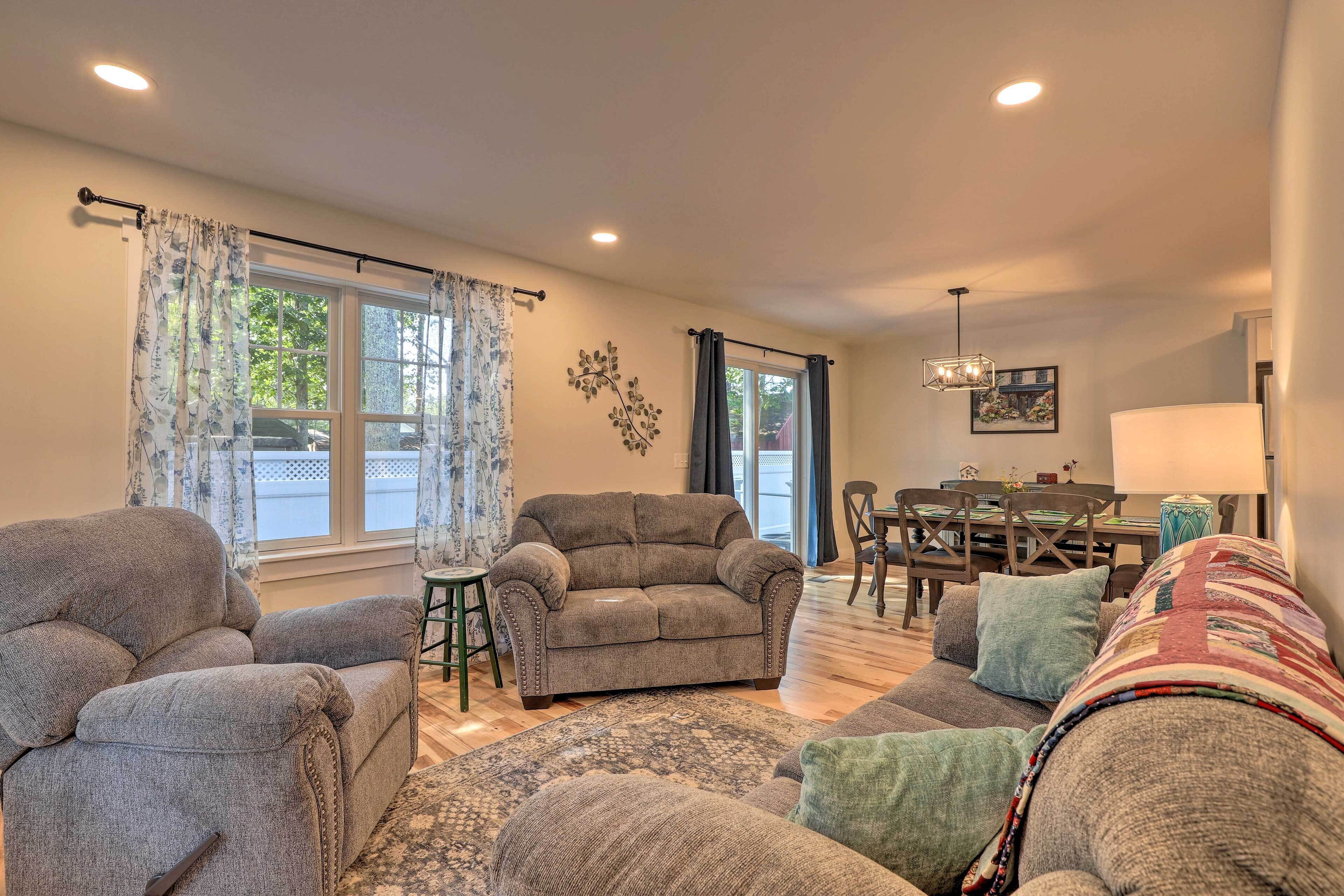 A living room with two grey sofas, a patterned rug, and a dining area with a table and chairs.