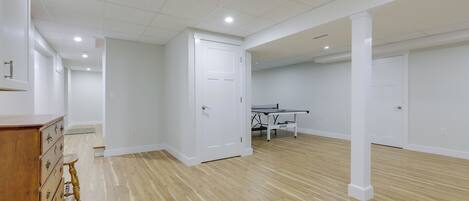 Una habitación amplia con piso de madera, paredes blancas y una mesa de ping pong.