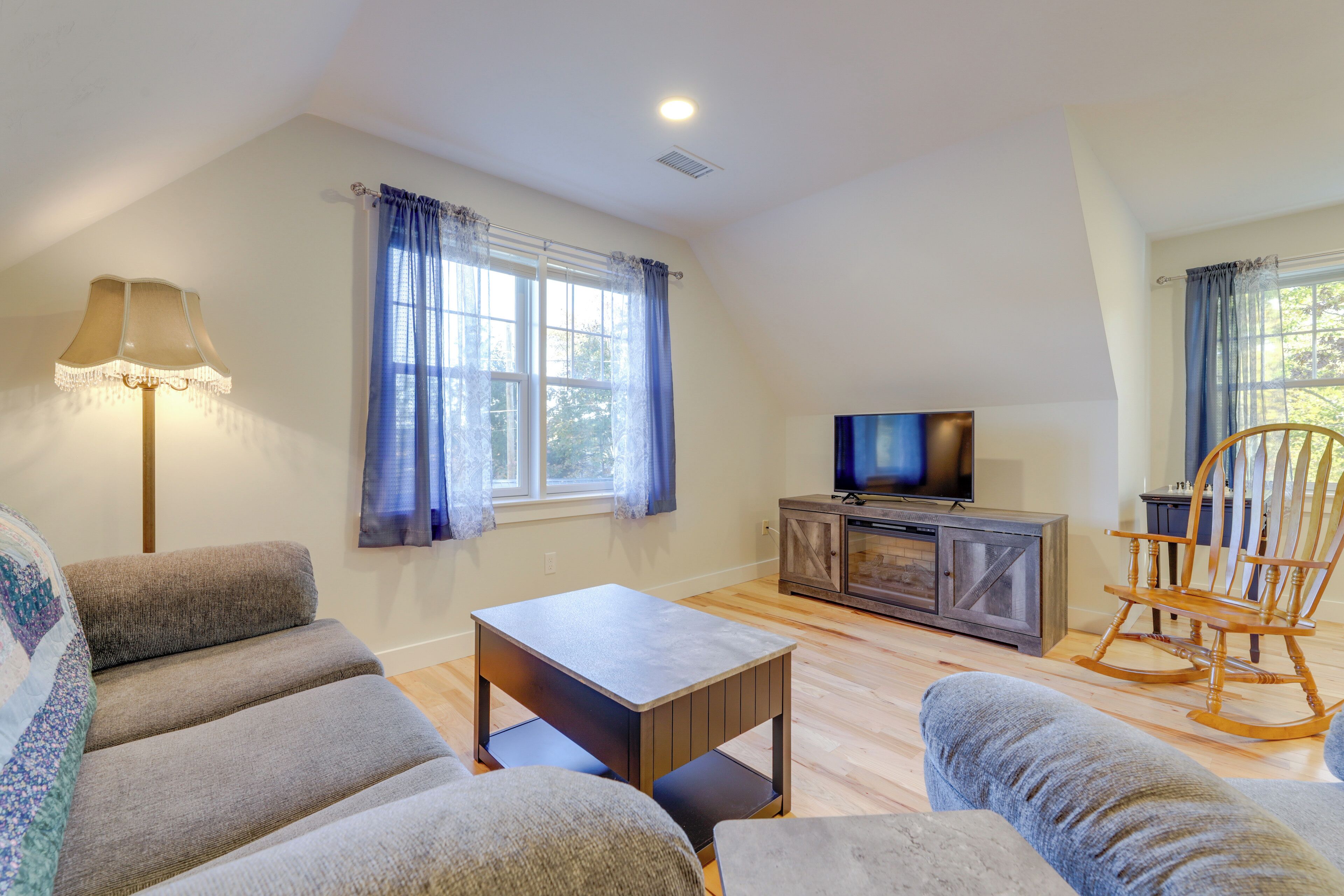 A living room with a sofa, a small table, a television, and a rocking chair.