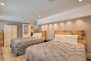 Een slaapkamer met twee bedden, een houten hoofdbord en een deur naar een andere kamer.