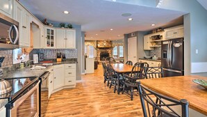 A spacious kitchen with wooden flooring, white cabinetry, and a central island with seating. - Charming Retreat ~ 1 Mi to Ossipee Lake Marina! (Center Ossipee)
