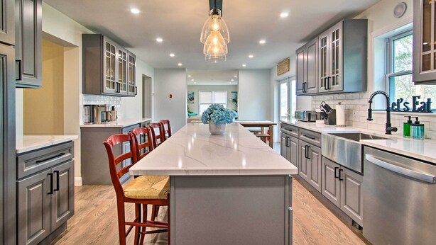 Eine moderne Küche mit einer zentralen Kochinsel, Edelstahlgeräten und einer Pendelleuchte.