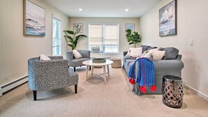 Ein Wohnzimmer mit grauem Sofa, Sesseln mit Muster und einem runden Couchtisch.