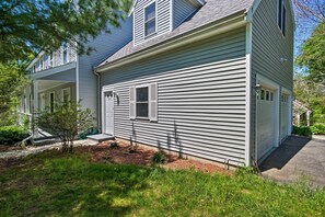 Ein zweistöckiges Haus mit Veranda, Garage und kleinem Vorgarten mit Baum und Mulch.
